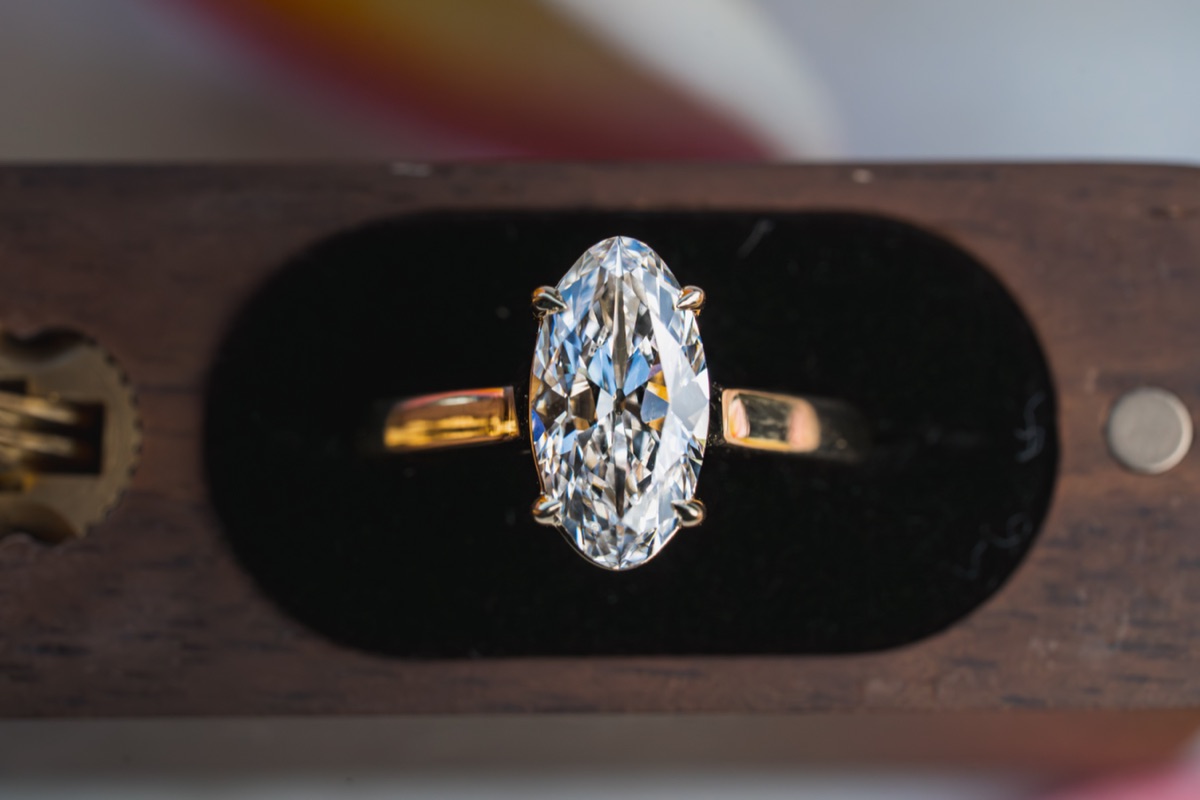 An oval diamond solitaire in its walnut ring box, finished.